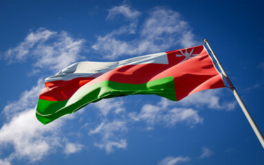 National state flag of Oman fluttering at sky background.