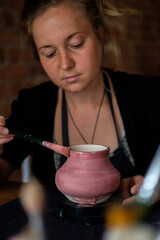 Fototapeta na wymiar Woman potter paints a handmade vase.