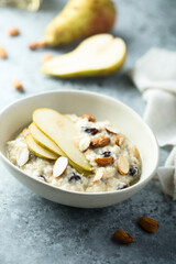 Fototapeta na wymiar Oatmeal porridge with nuts, raisins and fresh pear