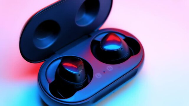 Black and pink earbuds on a case close up
