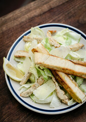 simple healthy chicken caesar salad on wood table