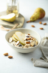 Fototapeta na wymiar Oatmeal porridge with nuts, raisins and fresh pear