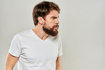 Obraz premium bearded man gesturing with his hands in a white t-shirt aggression light background