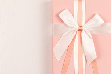 pink gift box with silk bright bow and ribbon on white wooden table