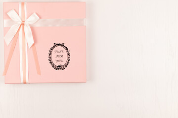 pink gift box with silk bright bow and ribbon on white wooden table