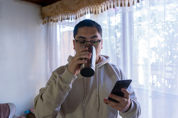 Man with checking his mobile phone and drinking coffee from a thermos