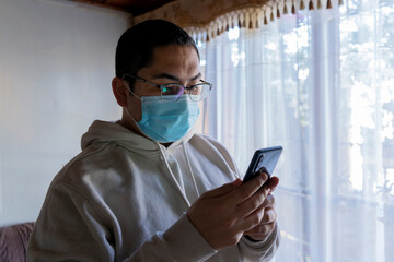 Man with mask looking at his mobile phone