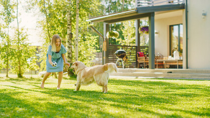 Cute Girl Has fun with Happy Golden Retriever Dog on the Backyard Lawn. She Plays Fetch with...