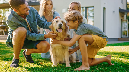 Smiling Beautiful Family of Four Posing with Happy Golden Retriever Dog on the Backyard Lawn. Idyllic Family Cuddling Loyal Pedigree Dog Outdoors in Summer House Backyard.