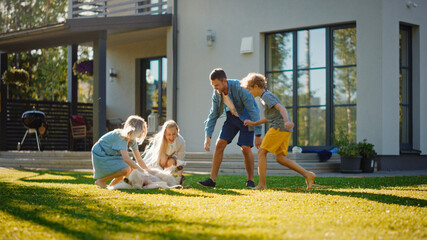 Beautiful Smiling Family of Four Cuddling Happy Golden Retriever Dog on the Backyard Lawn. Idyllic...