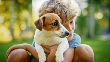 Cute Boy Holds His Favourite Pedigree Dog Friend while Having Picnic Outdoors on the Lawn. He Pets...