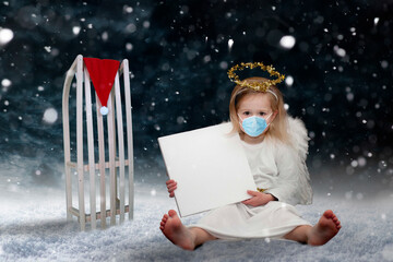 Christikind mit Mundschutz und Schild im Schneetreiben
