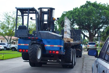 Fototapeta na wymiar Tractor with piggyback forklift trailer delivers to residential address.