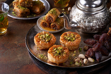 Middle eastern arab sweet pastry baklava, different delights, dried dates, pistachios, honey on a dark rusty background. Selective focus. Ramadan, Eid concept.