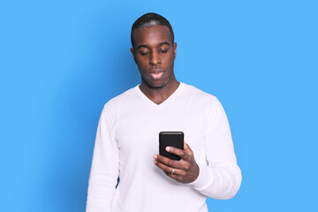Cheerful African American man in white sweater using mobile phone application.