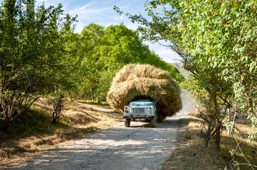 Old soviet truck full of hay. Tractor full with bale hay on village road near Sary Chelek lake,...