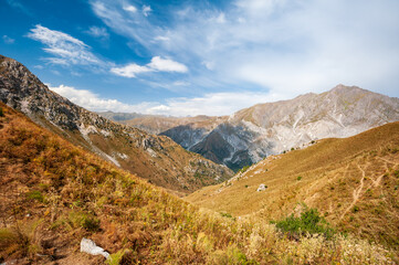 Rocky pass with mountain top views in high mountains. Young men and women hiking near Sary Chelek lake, Sary-Chelek Jalal Abad region, Kyrgyzstan, Trekking in Central Asia.