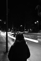 person walking in the street with lightstreams of cars 