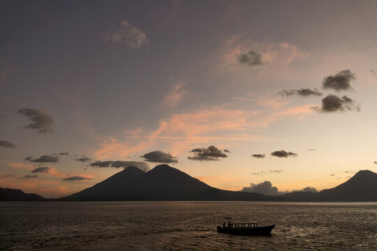 Guatemala, Central America: sunset with boats at lake Atitlán (Atitlan) with volcanos Atitlan, Toliman, San Pedro - Powered by Adobe