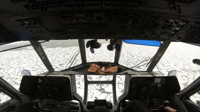 View of the cabin of mi-8 helicopter. Russian helicopter flies over chunks of ice in snow. Hand of the pilots at the helm of the helicopter. The helicopter is flying over the sea with ice.