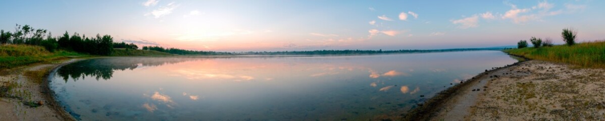 Obraz premium Panoramic view of a calm lake on a sunny summer day