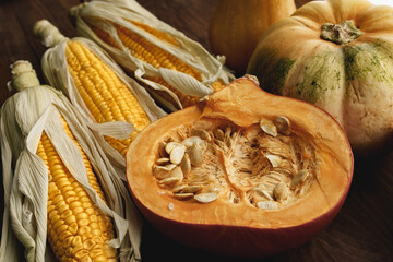Corn cob and pumpkin on brown wooden board