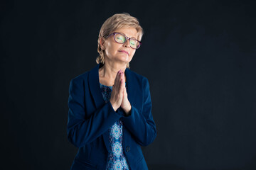 Beautiful older secretary praying wearing a blue suit