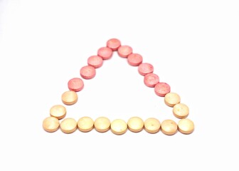 red or pink and yellow round pills isolated on white background creating a triangle 