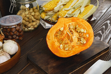 Corn cob and pumpkin on brown wooden board