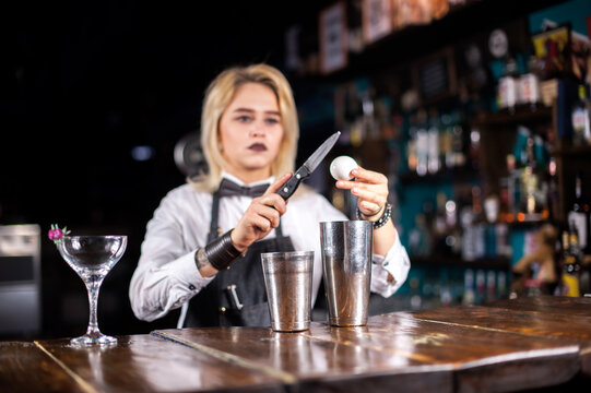 Girl barman formulates a cocktail in the taproom