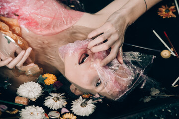 naked scared girl in the bath full of garbage, environmental or polution concept