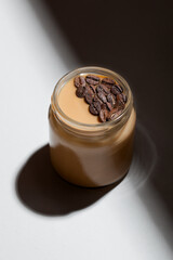 Coffee-flavored yogurt pudding dessert in glass jar on white background. Healthy lifestyle, superfood