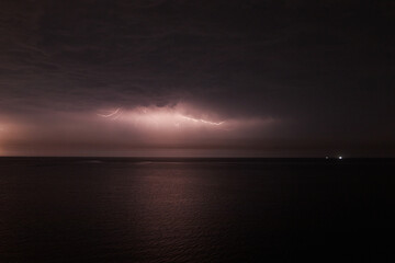 Fototapeta na wymiar Thunderstorm with lightning over the sea at night. Lightning flashes and storm clouds