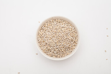 Unhulled barley in white bowl on white background 