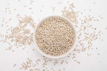 Unhulled barley in white bowl on white background 