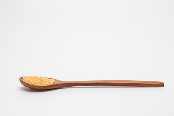 Wooden spoon with millet on white