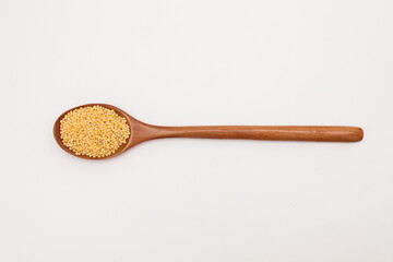 Wooden spoon with millet on white