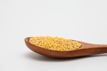 Wooden spoon with millet on white
