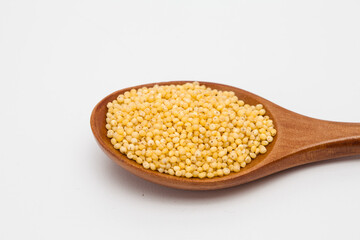 Wooden spoon with millet on white