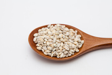 Wooden spoon with unhulled barley on white