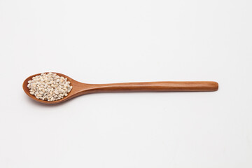 Wooden spoon with unhulled barley on white