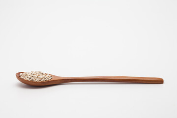 Wooden spoon with unhulled barley on white
