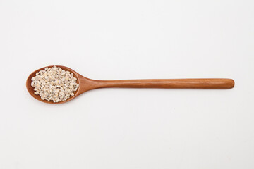 Wooden spoon with unhulled barley on white