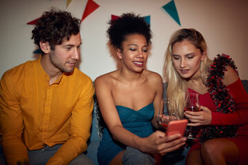  afro-american female showing content on her cell phone to a caucasian couple