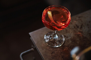 Red negroni cocktail on metal texture with orange peel