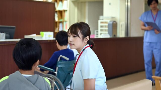 病院の待合室で患者の子供と話をする看護師