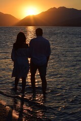 Silhouettes of girls and boys holding hands against the background of the sunrise in the sea. Sunrise in Icmeler.