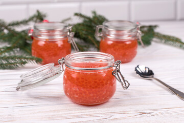 Red caviar in jar on aged white wooden background. Main dish New Year