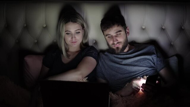 Man and woman, young couple watching boring movie on laptop in bed before bedtime