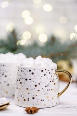 White cup of cappuccino or cocoa with christmas tree on the buckground of gold bokeh, New Year hot drink